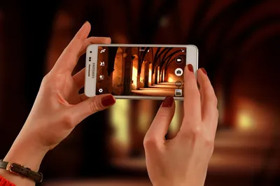 женщина держит белый смартфон Samsung Galaxy Android и фотографирует  прихожую · Бесплатные стоковые фото