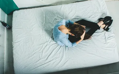 Девушка в джинсах и белом топике лежит на подушках в кровати - обои для  рабочего стола, картинки, фото