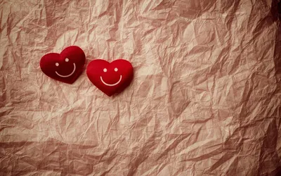 Обои на рабочий стол Два красных улыбающихся сердечка лежат на скомканном  листе бумаги, обои для рабочего стола, скачать обои, обои бесплатно