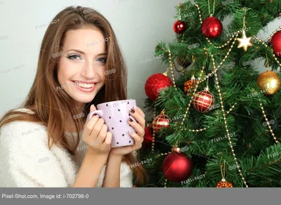 Милая девушка с кружкой в руках, на фоне новогодней елки. Stock Photo |  Adobe Stock